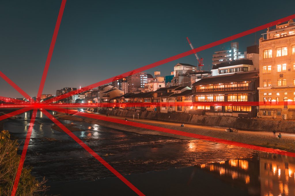 放射状構図の写真。川沿いの街並みの写真で、橋に向かって放射状に赤い線が引かれている。
