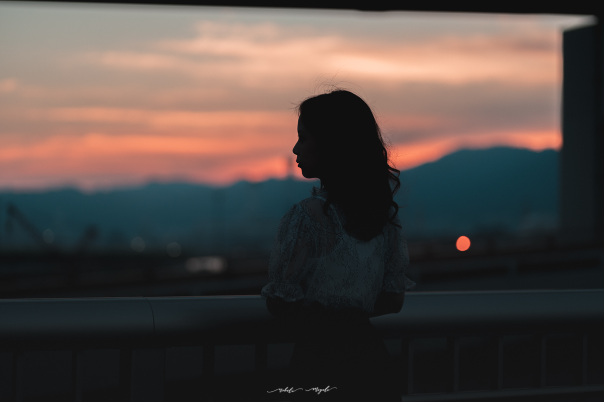 女性のポートレート写真。夕陽を見つめている。