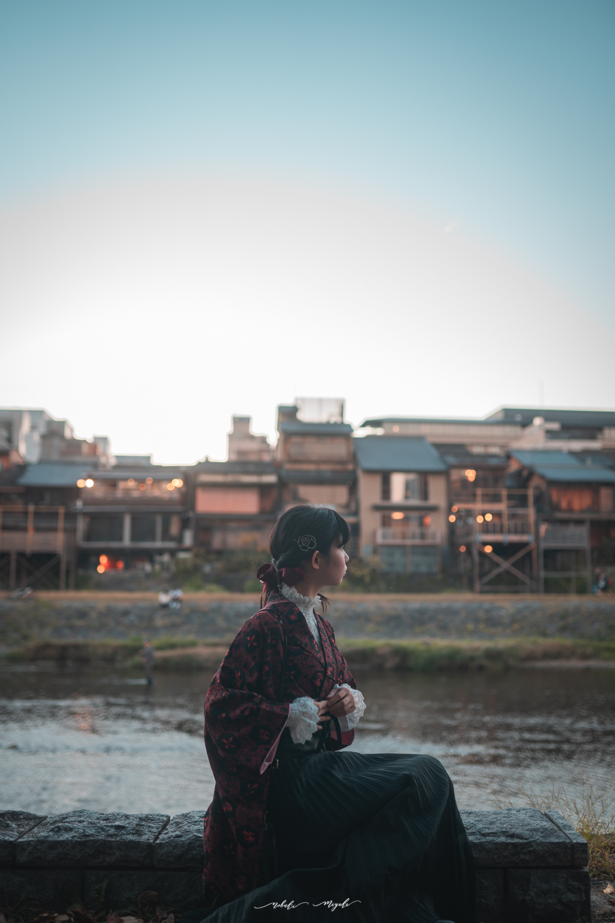 和装を着た女性のポートレート写真。鴨川を見つめている。