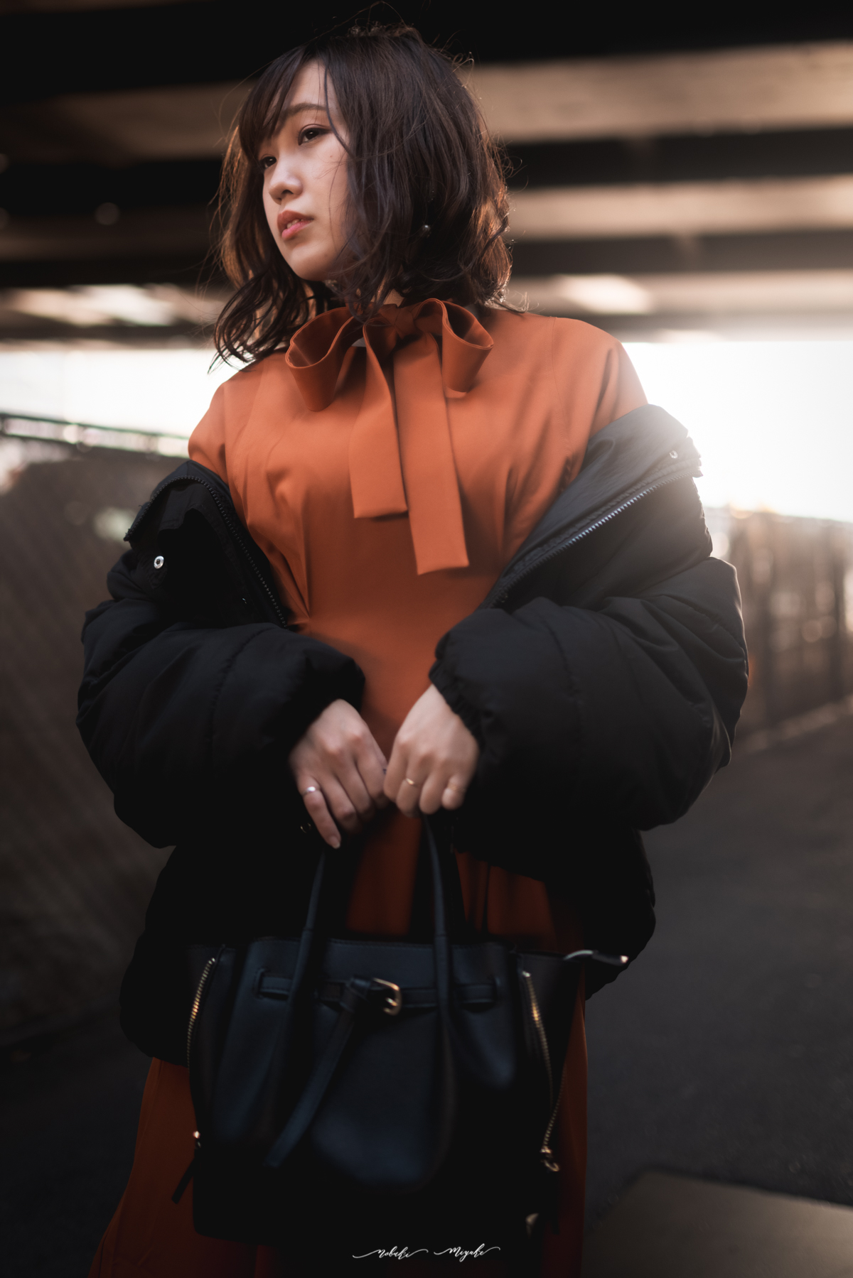 女性のポートレート写真。オレンジのワンピースとジャケットを着ている。